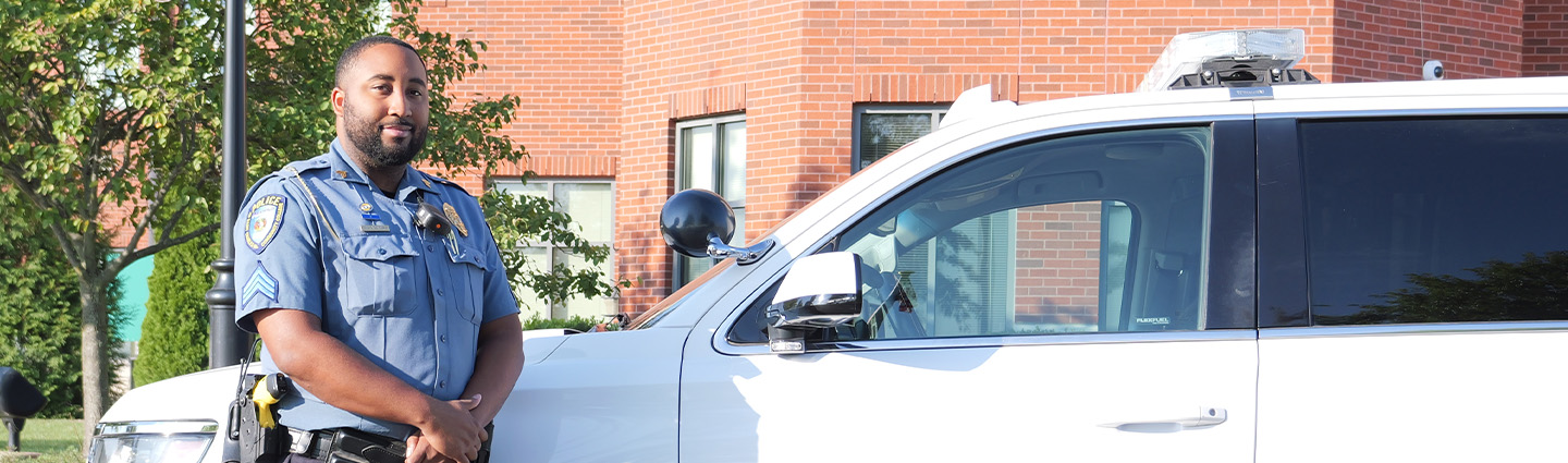 Campus Police Officer Standing in Front of Patrol Vehicle for Photo